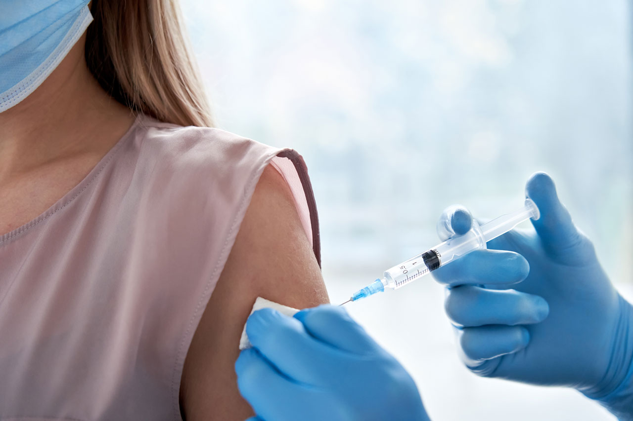 Ärztin spritzt junger Frau Schutzimpfung