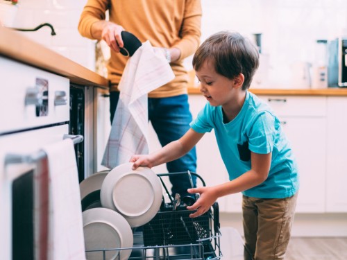 Sohn hilft Vater beim Ausräumen der Spülmaschine