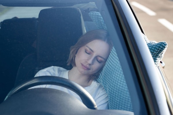Müde Frau schläft auf Kissen im Auto